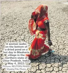  ?? Picture: REUTERS/Ritesh
Shukla/File Photo ?? A woman walks on the bottom of a dried pond on a hot day in Mauharia
village in the northern state of Uttar Pradesh, India,
May 4, 2022.