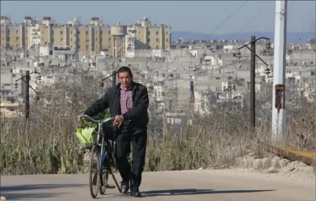  ?? Picture: AP ?? HOPE RETURNS: A resident seen pushing his bicycle in an area adjacent to the Waer neighbourh­ood in the central city of Homs, Syria, on Tuesday. Once Syrian rebels evacuate their stronghold, Homs once known as the ‘capital of the revolution’ will return...