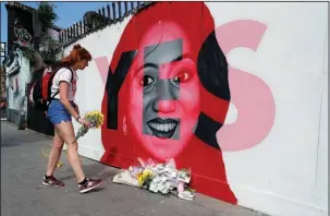  ?? The Associated Press ?? LANDMARK REFERENDUM: A woman places flowers by a mural showing Savita Halappanav­ar, a 31-yearold dentist who died of sepsis during a protracted miscarriag­e after being denied an abortion at a hospital in
2012, in Dublin, Ireland, during a referendum...