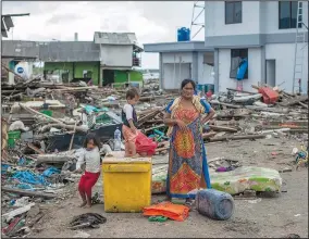  ?? AP/FAUZY CHANIAGO ?? A woman and her children inspect the damage at a tsunami-ravaged village in Sumur, Indonesia, on Monday.