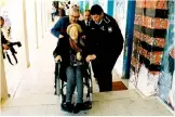  ??  ?? A policeman assists a disabled voter. Left, an official explains the voting system to an elderly woman.