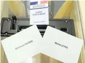  ??  ?? An electoral card is propped next to ballots for French presidenti­al election candidates on Friday.