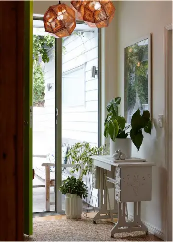  ??  ?? ENTRYWAY The lights by the front door are by Tom Dixon from ECC. Paula’s grandmothe­r’s Singer sewing table also takes pride of place. “I hauled it around with me for a long time, from flat to flat, knowing one day it would make a great entrance table,” she says.KITCHEN On a whim, Paula decided to get out the brushes and paint the kitchen ceiling dark green (Valspar ‘Cosmopolis’) – a crazy idea that worked.