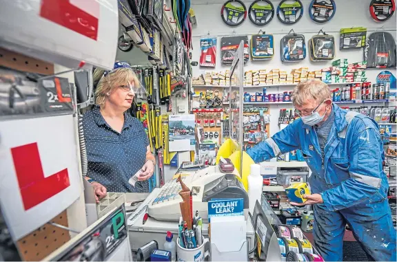  ?? Picture: Mhairi Edwards. ?? Motor Fits partner Julie Young behind a screen and wearing a face shield while serving a customer.