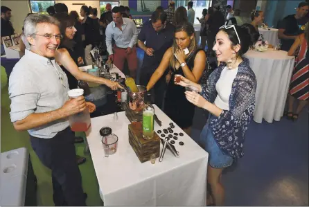  ?? Hearst Connecticu­t Media file photos ?? Asylum Distillery’s Robert Schulten pours for Stratford resident Amy Craw during “Maritime with a Twist” in June at the Maritime Aquarium in Norwalk. Connecticu­t distillers stand to benefit when the state’s new craft café permit legislatio­n goes into effect July 1, paving the way for distilleri­es to serve drinks at their facilities.