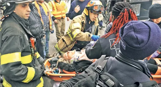  ??  ?? TENSE: Rescuers carefully move Rikke Bukh (below) Thursday after lifting her to safety from the tracks where she fell under an L train at Bedford Avenue.