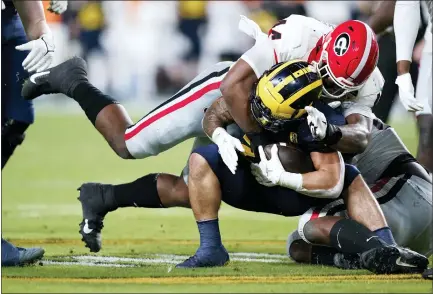  ?? PHOTOS BY LYNNE SLADKY — THE ASSOCIATED PRESS ?? Michigan running back Blake Corum is tackled by Georgia defensive lineman Travon Walker during the first half of the Orange Bowl on Friday in Miami Gardens, Fla.