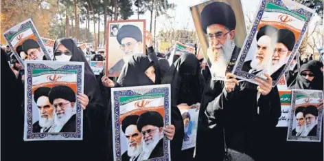  ??  ?? ► Manifestan­tes con carteles de los ayatolas Jamenei y Jomeini, durante una marcha oficialist­a ayer, en Qom.