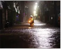  ?? AP/Kyodo News ?? A firefighte­r wades through a flooded street Saturday in Tokyo. Tokyo Electric Power Co. reported 432,000 households without power across Tokyo and Shizuoka.