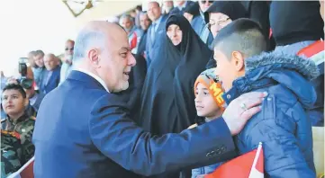  ??  ?? A handout picture released by the Iraqi Parliament’s press office shows Prime Minister Haider al-Abadi greeting an Iraqi child in Baghdad at the start of a military parade to mark the end of a three-year war against the Islamic State group. Haider...