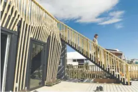 ?? Helen H. Richardson, The Denver Post ?? Brenton Kreiger, a member of the team from the University of California-Berkeley, on Wednesday walks down the stairs outside its solar home, which is competing in the U.S. Department of Energy Solar Decathlon in Denver. The exterior wood paneling is a...