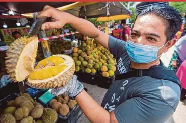  ?? BERNAMA PIC ?? 9932 Durian Stall owner Wan Mohd Faizal Wan Mohd Noor holding up a Musang King durian at his stall in Jalan Tok Kenali, Wakaf Stan, Kota Baru.