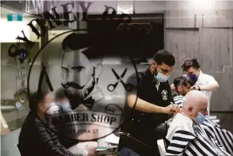  ?? Rick Rycroft / Associated Press ?? Barbers in Sydney trim their first costumers in months after a lockdown was lifted for people who are vaccinated. While cases have slowed in Sydney, they have yet to peak in Melbourne.