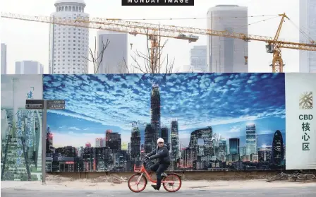  ?? | Reuters ?? A MAN cycles outside the constructi­on sites in the central business area of Beijing, China, at the weekend.