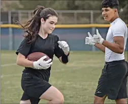  ?? Dan Watson/The Signal ?? (Above) Teammate Jonah Arrue gives the thumbs up to freshman Katya Way as she runs drills with the Wildcats’ junior varsity football team at West Ranch High School on Wednesday. (Left) Way gets her assignment from coach Rick Miler as they run drills with the Wildcats’ junior varsity football team.