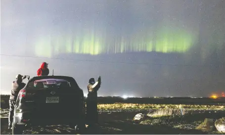  ?? MICHELLE BERG ?? People pulled over on the side of 8th Street East to get a glimpse of the Aurora Borealis — the northern lights — during a massive solar storm on Sunday. The storm made the lights visible throughout North America, even in areas where they normally are not seen.