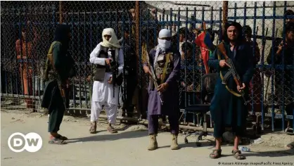  ??  ?? Taliban fighters and Pakistani soldiers stand guard at a border crossing point between Pakistan and Afghanista­n in Torkham