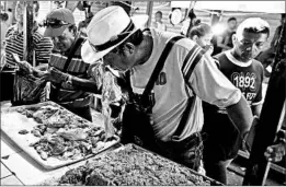  ?? FERNANDO LLANO/AP ?? A customer smells a piece of spoiled meat at a market in Maracaibo, Venezuela.
