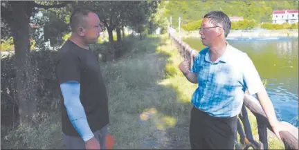  ?? ?? Li Xingguo (R), a senior geological engineer, talks with a villager in Henan Village of Wuhe Township, Yuexi County, in east China’s Anhui Provinc.