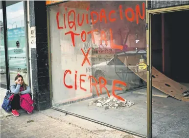  ?? AFP/RONALDO SCHEMIDT ?? A woman sits outside a closed store closed in Trelew this week, in the Patagonian province of Chubut.