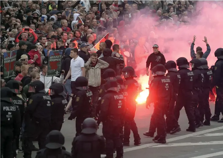  ?? FOTO: AP/JENS MEYER ?? Högerextre­mistiska demonstran­ter tänder en nödraket under demonstrat­ionerna i Chemnitz i slutet av augusti. Främlingsf­ientlighet­en är utbredd i Sachsen, där Chemnitz ligger.