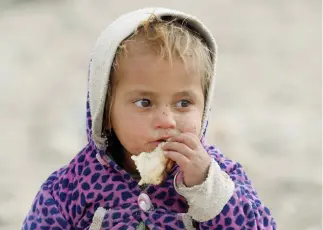  ??  ?? An internally displaced Afghan child eats bread outside the shelter at a desert in Khogyani district of Nangarhar province, on Tuesday. (Reuters)