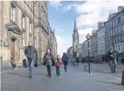  ??  ?? A family walks down a street in Edinburgh on Tuesday. Scotland’s leader Nicola Sturgeon announced on Monday she will seek authority to hold a new independen­ce referendum in the next two years.