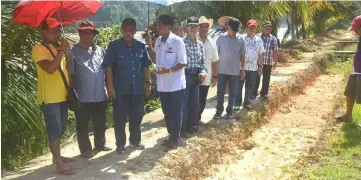  ??  ?? Jamit (third left) and others checking the drain to ensure that water does not flow directly down the river bank.