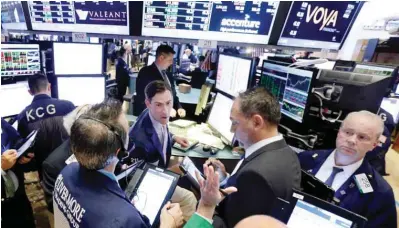  ??  ?? NEW YORK: Traders gather at the post of specialist John McNierney, background center, at the end of the trading day, on the floor of the New York Stock Exchange on Thursday. — AP