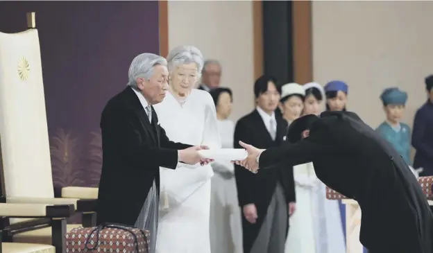  ?? PICTURE: AFP/GETTY IMAGES ?? 0 Emperor Akihito hands over his statement to the chamberlai­n after delivering his speech during the abdication ceremony yesterday