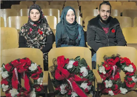  ?? MICHAEL BELL ?? From left, Mays Al Jamous, Nour Albaradan, and Abdul Mustafa sit in the auditorium of Sheldon-Williams Collegiate. The students will share their memories of war-torn Syria as part of the school’s Remembranc­e Day service on Friday.