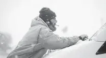  ?? Bryon Houlgrave / Associated Press ?? Joe Strand cleans the windshield wipers of his van in a hotel parking lot in Altoona, Iowa, as snow falls around him Friday.