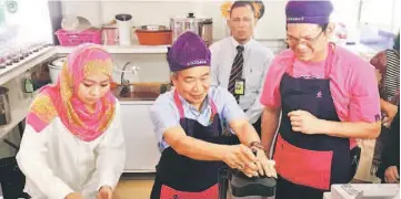  ??  ?? Naroden (centre) tries his hands making his own smoothies at the Cool Blog outlet at Kuching Internatio­nal Airport. Leong is seen on the right.