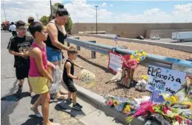  ?? AP PHOTO/ANDRES LEIGHTON ?? An El Paso family brings flowers Sunday to the makeshift memorial for the victims of Saturday’s mass shooting at a shopping complex in El Paso, Texas.