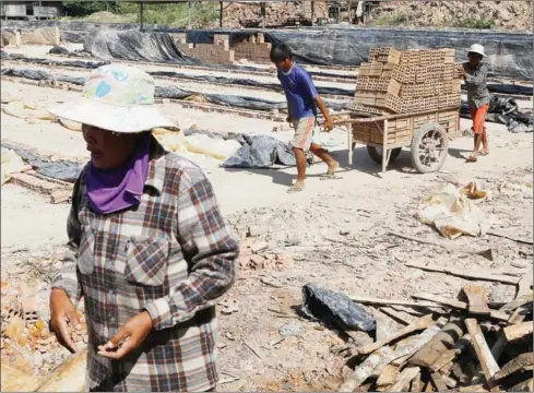  ?? PHA LINA ?? Mother-of-two Von Pho walks through a brick factory in Kandal province last month. Pho earns about $2 per day, and estimates that with this salary she will remain in debt to the factory’s owner for up to two decades.