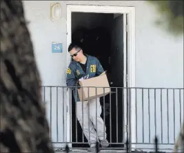  ?? Rich Pedroncell­i ?? The Associated Press A federal agent removes items from an apartment following the arrest of Omar Ameen on Wednesday in Sacramento, Calif.