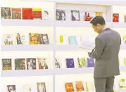  ?? Mary Altaffer / Associated Press ?? A visitor inspects books Wednesday at the China pavilion at BookExpo America in New York. The convention’s largest presence at BookExpo, covering 23,000 square feet, is China and its publishers.