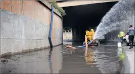  ?? PICTURE: ITUMELENG ENGLISH ?? WATER UNDER THE BRIDGE: Workers battle to drain the overflowed Smit Street off-ramp in Braamfonte­in caused by the storm in Joburg.