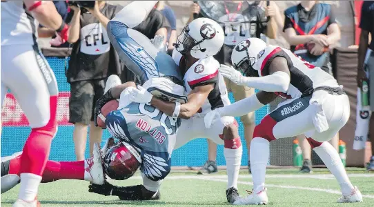  ?? GRAHAM HUGHES/THE CANADIAN PRESS ?? Redblacks defenders upend the Alouettes’ Tyrell Sutton in the first half in Montreal on Sunday. The Redblacks won 29-11.