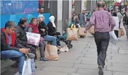  ??  ?? LONDON: Shoppers sit with their purchases in bags outside a Primark store in central London yesterday. — AFP