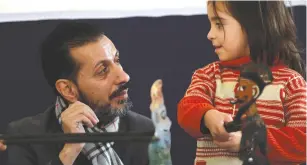  ??  ?? SHADI AL-HALLAQ, a puppeteer, is seen next to a disabled child during a performanc­e in Damascus earlier this month.