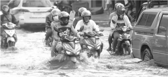  ?? JOY TORREJOS ?? Motorists wade through a flooded road in Barangay Tipolo, Mandaue City following a heavy downpour yesterday.