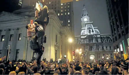  ?? MATT ROURKE/AP ?? Eagles fans climb a light pole as hundreds look during during celebratio­ns Sunday night in Philadelph­ia following the Eagles’ 41-33 win over the New England Patriots in Super Bowl 52. Police say the vast majority of revelers were peaceful and police...