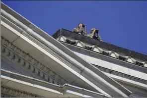  ?? Arkansas Democrat-Gazette/STATON BREIDENTHA­L ?? Uniformed personnel look through binoculars Monday from the roof of the state Capitol during a protest over the police shooting of Bradley Blackshire.