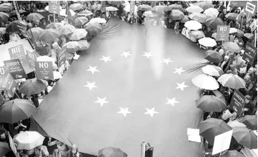  ??  ?? File photo shows people deploying a giant European flag during a demonstrat­ion against government plans of judicial system reforms in front of the European Commission Representa­tion office in Warsaw. — AFP photo