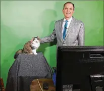  ?? CONTRIBUTE­D BY NATALIE LYONS ?? Jeff Lyons, a meteorolog­ist in Evansville, Indiana, does a forecast with his cat, Betty, from his dining room recently. The station even created a “Betty the Weather Cat” graphic.