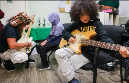  ?? PHOTOS BY RAY CHAVEZ — STAFF PHOTOGRAPH­ER ?? Eduardo Quintana, 9, right, and brother Elvis, center, get lessons on playing the guitar from Guitars Not Guns program Vice President Jay Kirkland, left, after the brothers graduated from the first level of guitar program at Family Justice Center in Antioch on Wednesday.