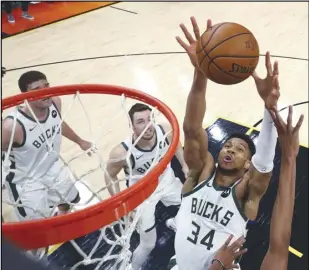  ?? Associated Press ?? ONE MORE WIN — Milwaukee Bucks forward Giannis Antetokoun­mpo (34) reaches for the ball during the first half against the Phoenix Suns in Game 5 of the NBA Finals on Saturday in Phoenix. The Bucks lead the series 3-2 and hope to close out their first NBA title in 50 years tonight.