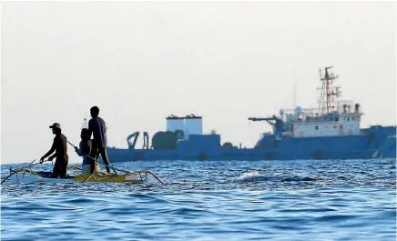  ?? PHOTO: REUTERS ?? Filipino fishermen pass a large Chinese vessel at the disputed Scarboroug­h Shoal.