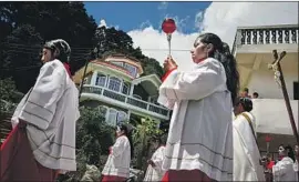  ??  ?? RESIDENTS take part in a Catholic procession through town. In the background, a home that was built with money remitted from work in the U.S.